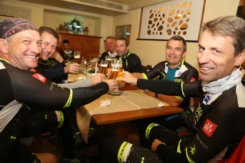 Fünf Fahrer stoßen mit Bier an einem Tisch an