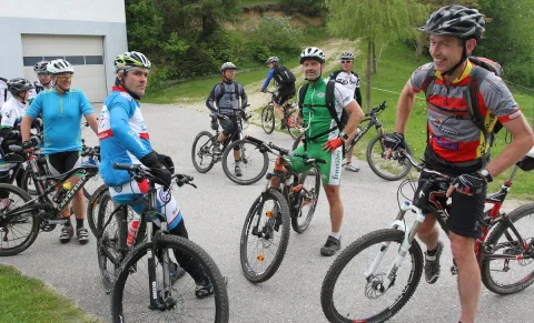 Eine Gruppe Radfahrer steht mit ihren Rädern auf einem Platz beisammen