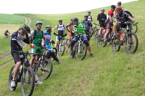 Eine Gruppe Mountainbiker fährt gemeinsam einen Wiesenweg hinauf