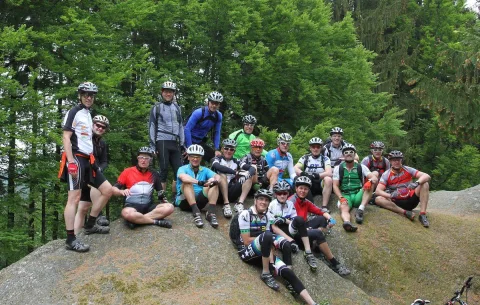 Die Teilnehmer sitzen zum Gruppenbild auf einem Felsen am Waldrand