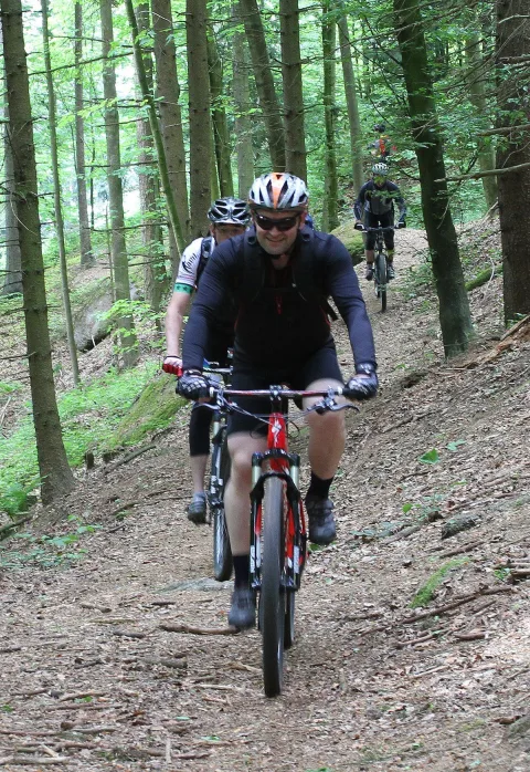 Ein Radfahrer in dunkler Jacke fährt auf die Kamera zu