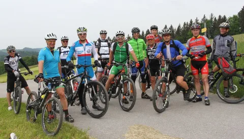 Eine Gruppe Radfahrer steht mit ihren Rädern am Waldrand beisammen