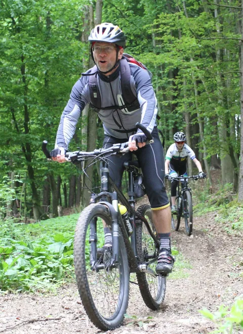 Zwei Mountainbiker fahren hintereinander einen Waldweg hinauf