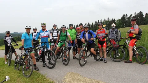 Eine große Gruppe Radfahrer steht mit ihren Rädern zum Gruppenbild auf einem Feldweg