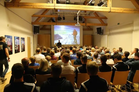 Blick über das Publikum im Saal zur Leinwand mit dem Vortragsbild