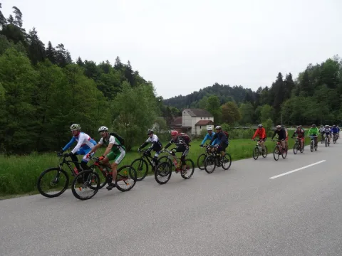 Eine Gruppe Rennradfahrer fährt auf einer Landstraße durch eine Ortschaft