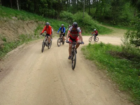 Zwei Mountainbiker fahren einen Schotterweg entlang, ein dritter folgt
