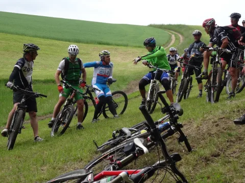 Mehrere Mountainbiker fahren einen Wiesenweg entlang, im Hintergrund Felder