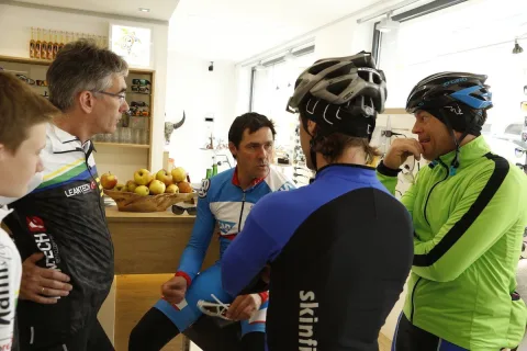 Radfahrer stehen nach der Ausfahrt im Geschäft zusammen, einer trägt noch den Helm