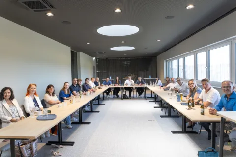 Blick von der Stirnseite durch den Saal auf zwei lange, voll besetzte Tischreihen