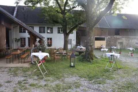 Vor einem Gebäude stehen viele Tische und Stühle im Gras.