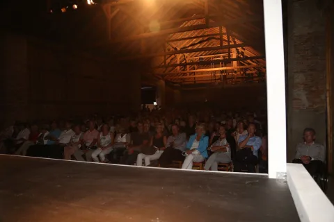 Eine große Gruppe von Menschen sitzt in einem dunklen Auditorium.