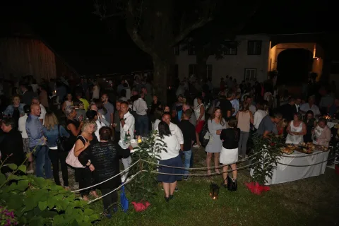 Eine große Gruppe von Menschen steht nachts um einen Tisch herum.
