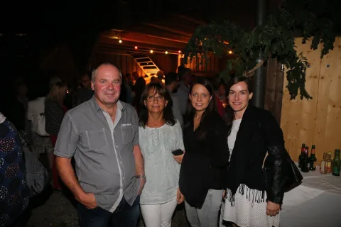 Eine Gruppe von Menschen posiert in einem dunklen Raum für ein Foto.