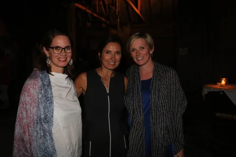 Drei Frauen posieren in einem dunklen Raum zusammen für ein Foto.