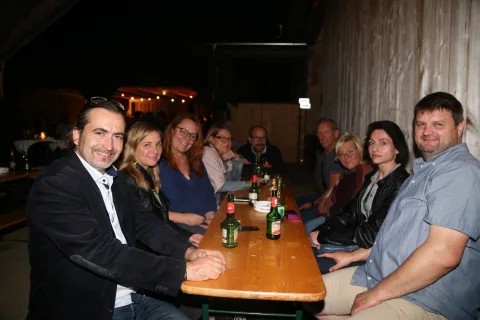 Eine Gruppe von Leuten sitzt mit Bierflaschen an einem Tisch.