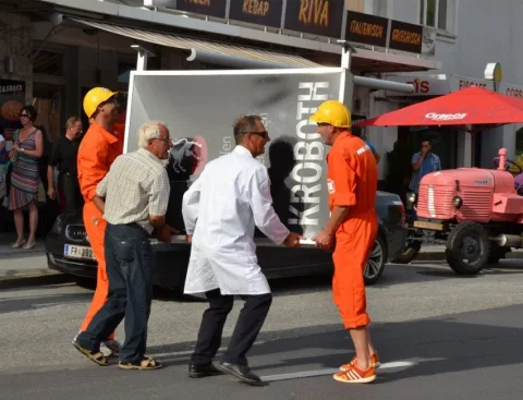 Eine Gruppe Männer schiebt eine Kiste mit der Aufschrift „Kroboth“