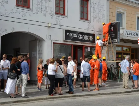 Helfer auf einer Leiter an der Hausfront, davor Besucher