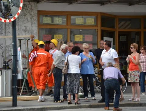Ein Helfer in orangem Overall neben Besuchern