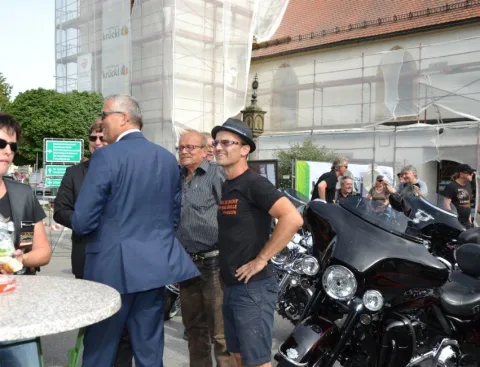 Gäste an einem Stehtisch neben Motorrädern