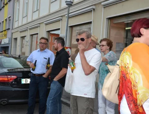 Gäste mit Flaschen vor einem Auto