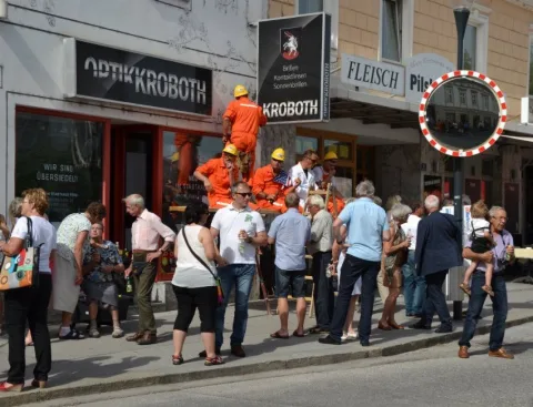 Besucher vor dem Geschäft, ein Helfer auf der Leiter