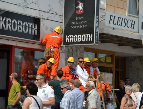 Helfer in orangen Overalls unter dem Kroboth-Schild