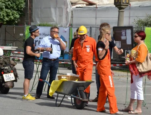 Gäste und ein Helfer mit Schubkarre auf der Straße
