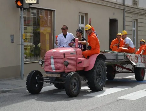 Ein rosa lackierter Oldtimer-Traktor mit Anhänger