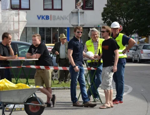Helfer in Warnwesten neben einer Schubkarre