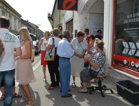 Besucher vor dem Schaufenster mit der Aufschrift „Wir sind übersiedelt“