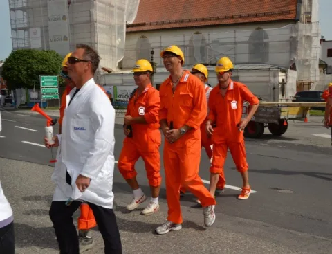 Helfer in orangen Overalls gehen die Straße hinunter