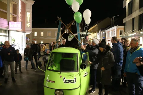 Besucher auf dem Platz, dahinter beleuchtete Häuser