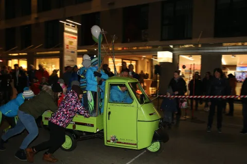 Ein Kind schiebt den Kleintransporter, dahinter Zuschauer