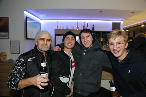 Vier Gäste mit Flaschen vor der Bar