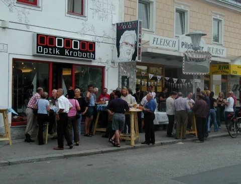 Gäste an Tischen auf der Straße vor dem Geschäft