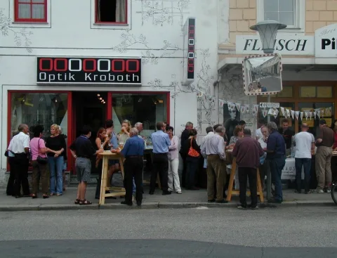Besucher an Stehtischen vor der Schaufensterfront